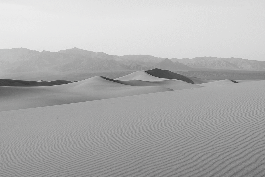 “Black and white photo of an expansive desert landscape with soft dunes and distant mountains, symbolizing clarity, solitude, and inner reflection.”